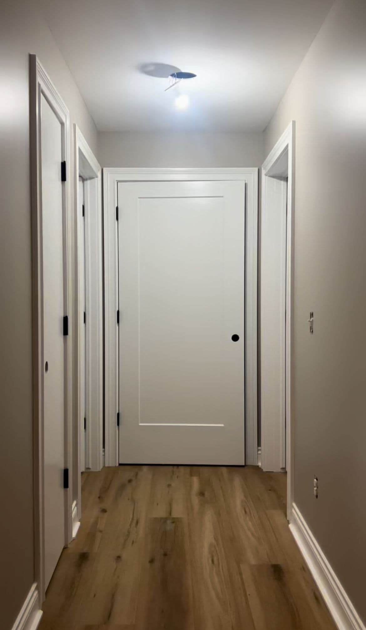 a long hallway with a white door and wooden floors