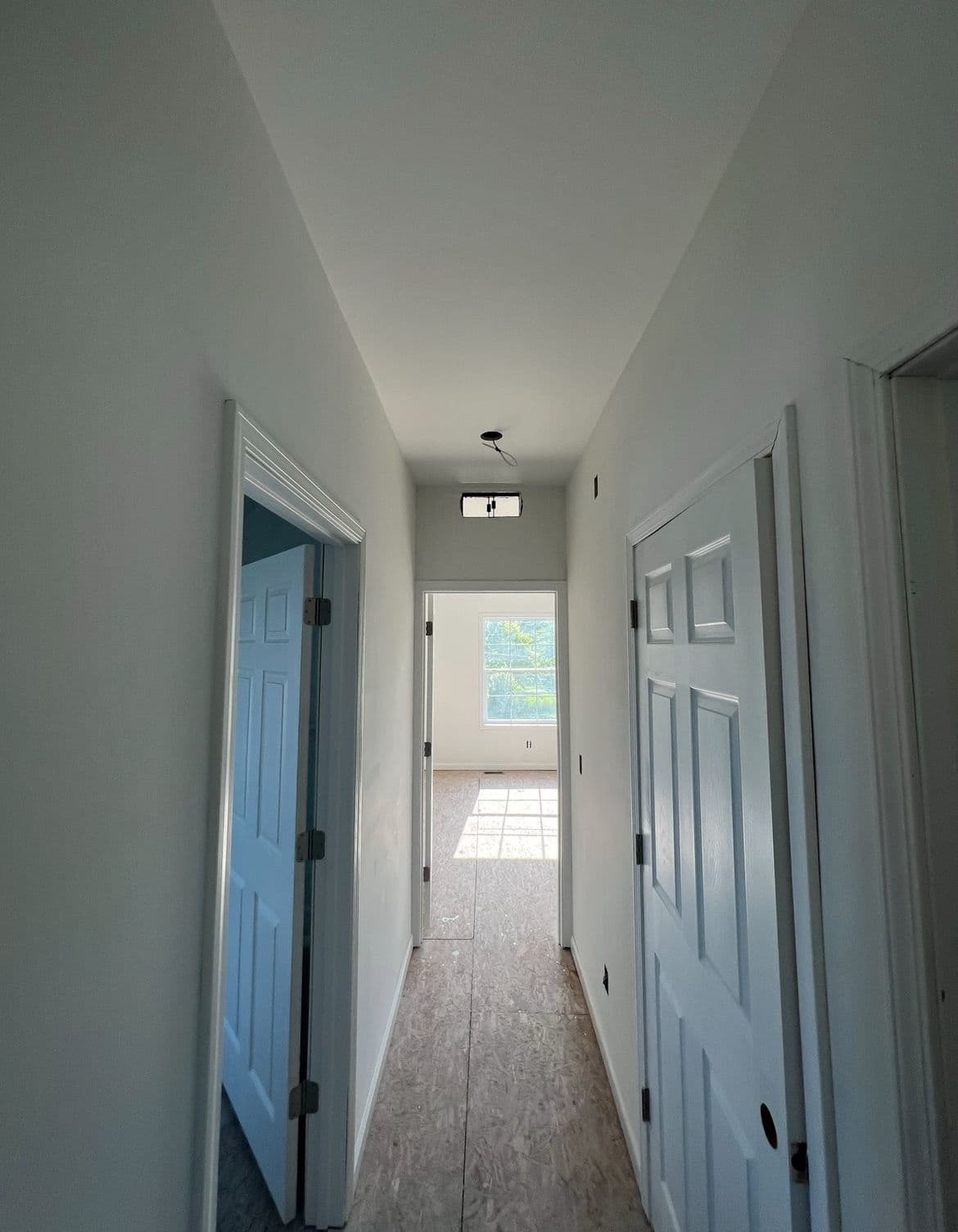a long hallway with two doors leading to another room
