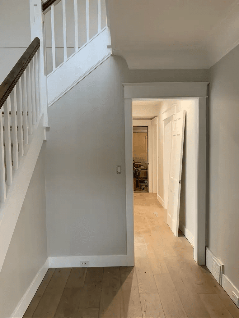 a hallway with a wooden floor and white railing